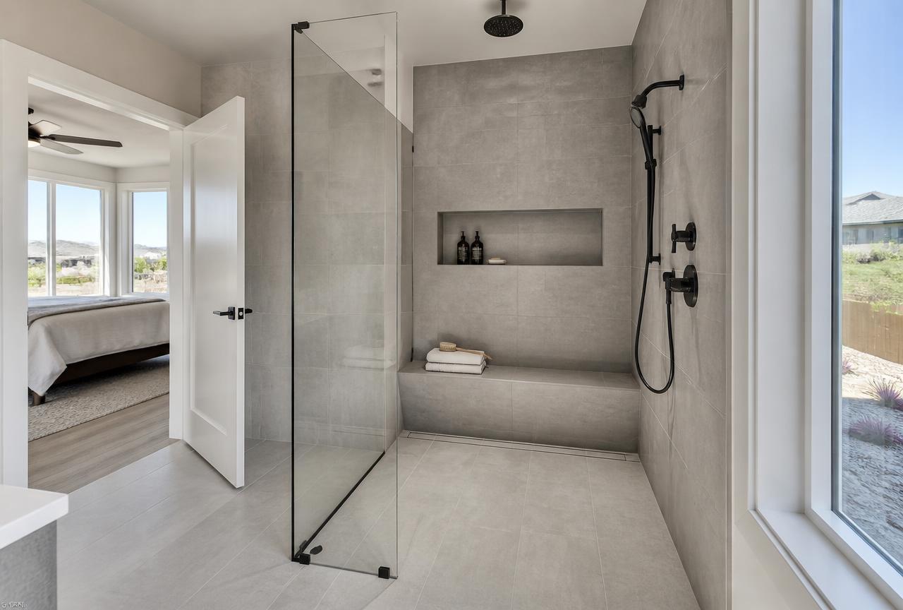 Finished curbless walk-in tile shower in a Meridian, Idaho master bathroom with a linear drain, tiled bench and frameless glass panel