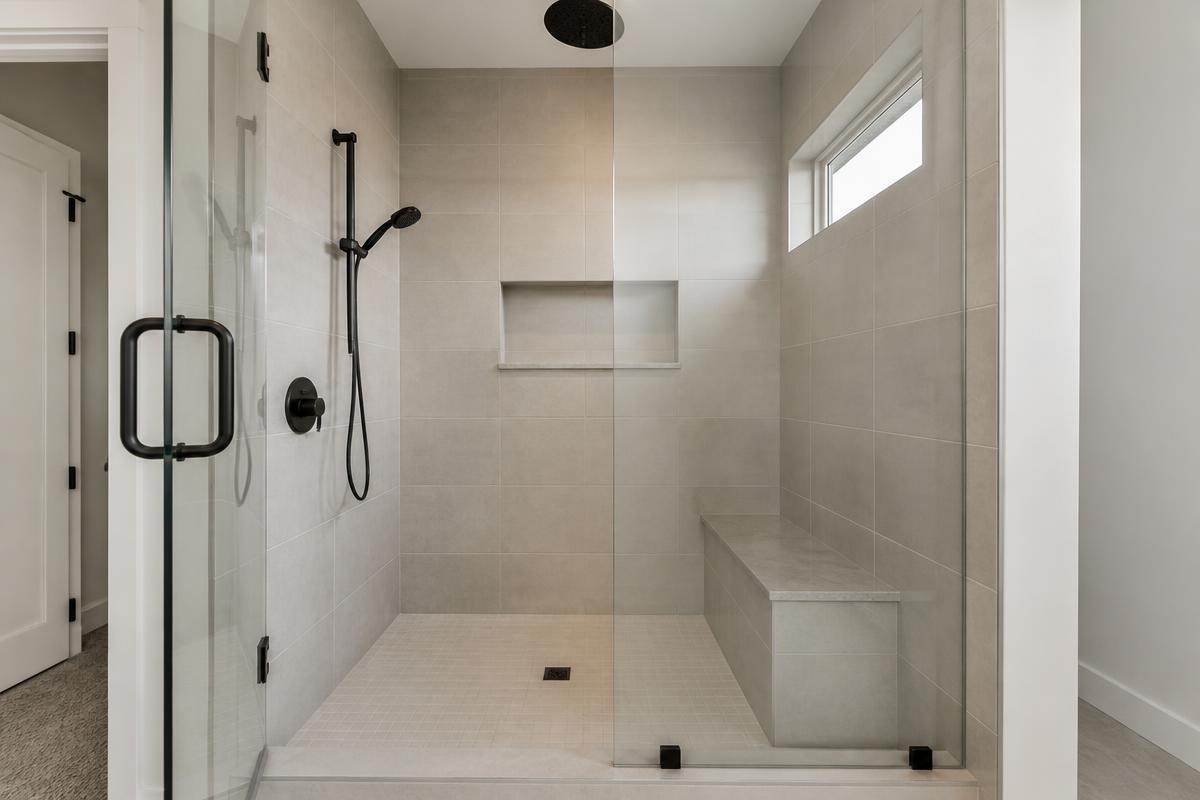 Remodeled shower in a Meridian, Idaho home with large-format porcelain tile, a recessed niche and a frameless glass door